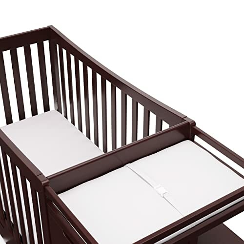 Wooden baby crib with white mattress.